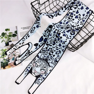 Detail of long silk scarf with leopard print and cartoon cat head on white background