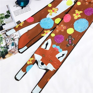 Detail view of brown silk scarf with fox and gingerbread man patterns and flat lay props