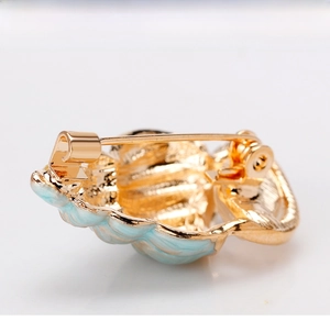 Detail view of the back side of a light blue conch brooch with a secure gold-tone safety pin