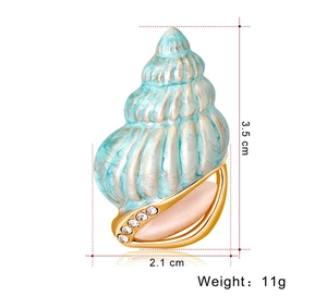 Detail view of light blue conch brooch with gold trim and rhinestones showing dimensions