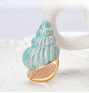 Macro detail of light blue enamel conch brooch with pink cat eye stone and rhinestones