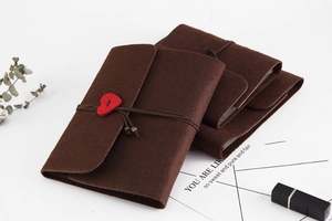Detail of dark brown felt DIY scrapbook with a red heart button and string closure