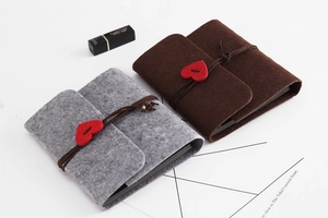 Flat lay of brown and gray felt DIY scrapbooks with heart buckle and leather strap binding