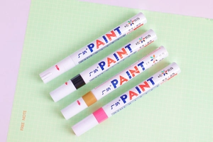 Detail of oil-based paint markers in white gold and black on grid background
