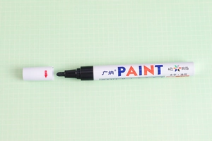 Detail shot of the white paint marker nib and barrel on a green grid cutting mat