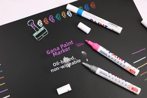 Macro detail of GANA SP110 oil-based paint markers in pink silver blue on black board