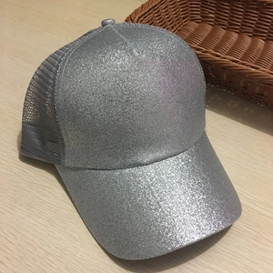 Dettaglio macro del cappellino con paillettes argento e rete grigia su tavolo in legno