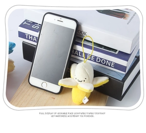 Close-up of cute peeled banana plush pendant on wooden tray with phone for scale