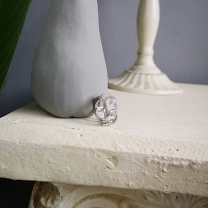 Macro view of interlocking silver link ring with pave zircon stones on stone base