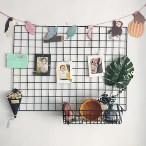 Détail d'un panneau mural en grille métallique noire avec panier de rangement intégré