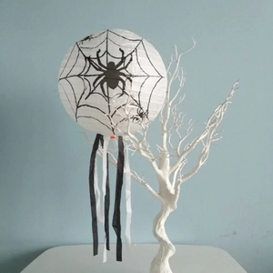 Halloween white paper lantern with black spider web patterns and decorative fringe