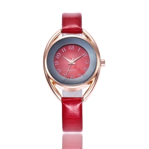 Detail view of red leather watch strap and rose gold bezel with oval decorative elements