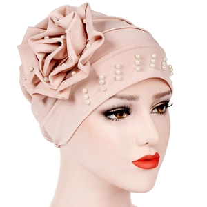 Detailed view of the large three-dimensional flower and white pearls on the pink turban hat