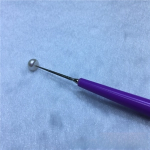 Detail of purple jewelry reamer tool enlarging hole on a white freshwater pearl