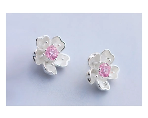 Macro detail of cherry blossom stud earrings with white enamel and pink zircon stone