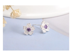 Macro detail of silver cherry blossom stud earring with purple zircon center and matte petals