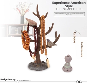 Detailed view of branch-style jewelry stand with bird accents and amber beads on rock base