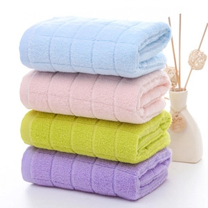 Détail de serviettes en coton empilées en bleu, rose, vert et violet avec motif gaufré