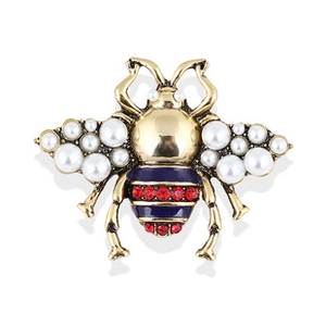 Close-up of golden bee brooch with white pearls and sparkling red rhinestones