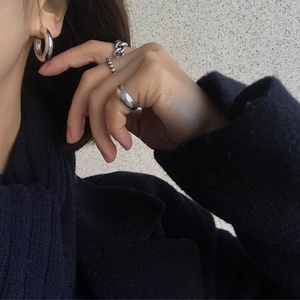 Detail shot of minimalist silver twisted rope and chain rings worn on a hand