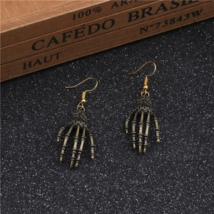 Detail of vintage bronze skeleton hand earrings on a dark glitter background