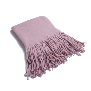 Close-up of pink knit scarf showing thick soft texture and long fringe tassels details
