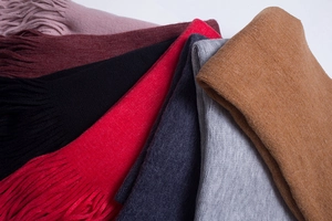 Close-up of thick tassels and soft knitted texture on colorful winter scarves