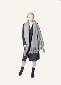 Gray long fringed scarf styled with a black coat and blue jeans for a winter look