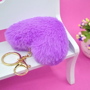 Vista macro detallada de un llavero de corazón de peluche morado en un banco de madera