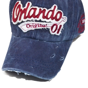 Detail of distressed navy denim baseball cap with 3D Orlando embroidery and frayed edges