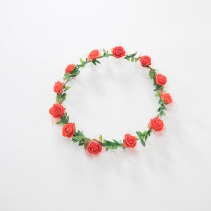 Detailed view of artificial red foam roses and green leaves on a floral headband crown