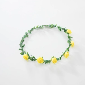 Detail view of yellow foam roses and green leaf accents on a floral headband accessory