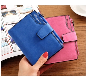 Close-up of pastel pink and blue PU leather wallets with snap buttons on a wooden desk