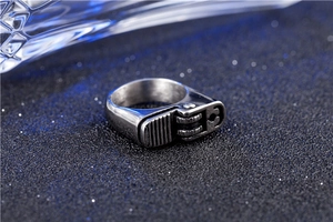 Macro shot of retro silver lighter-shaped titanium steel ring on dark blue textured surface