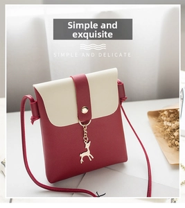 Close-up of a mini red and beige phone crossbody bag with a golden deer charm detail
