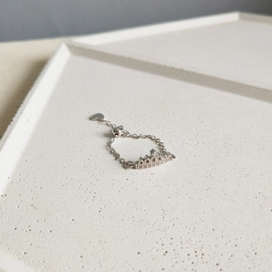 Detail of silver crown ring with cubic zirconia inlay and adjustable heart pendant