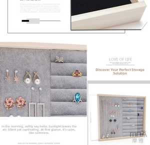 Detail of wooden jewelry box featuring ring slots, earring hooks and grey velvet lining