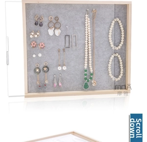 Detail of wooden jewelry display board with grey velvet lining showing necklaces and earrings