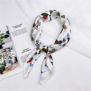 Silk-like white square scarf with zebra and heart patterns next to a lifestyle magazine