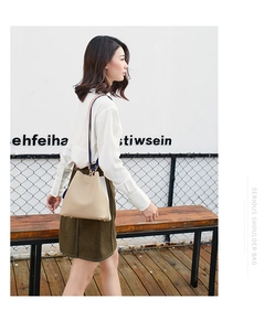 Detail view of cream leather bucket bag featuring a vibrant contrast wide shoulder strap