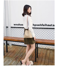 Outdoor model display of a beige bucket bag showing its size and metal studs on the base