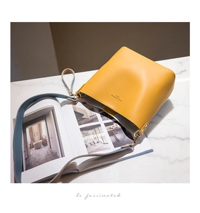 Detailed macro view of yellow bucket bag with contrast blue strap and gold hardware