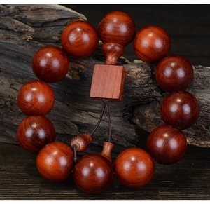 Macro shot of 12 rosewood prayer beads with a square wooden plaque on aged wood
