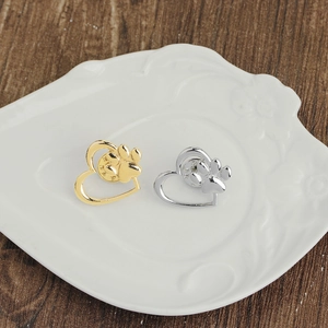 Gold and silver heart paw brooches displayed on a textured white ceramic plate