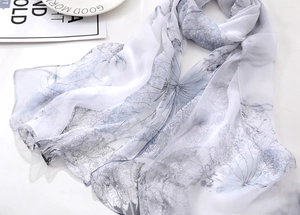 Detailed close-up of light chiffon silk scarf featuring blue ink floral leaf prints