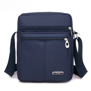 Macro view of blue Oxford fabric messenger bag with metal logo and layered zipper pockets