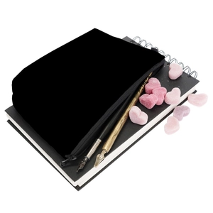 Close-up of black sunflower cosmetic bag with vintage pens and notebooks on white background