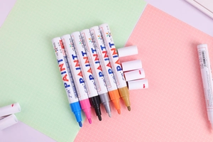 Detailed view of six colorful oil-based paint markers with medium tips on grid background
