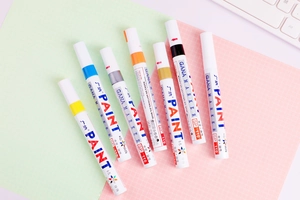 Assorted colors of quick-drying oil-based paint markers on a pastel workspace background