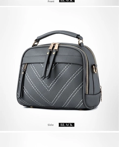 Close-up of grey pebbled leather handbag with white V-quilted stitching and gold hardware